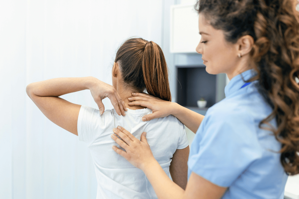 Physical therapist performing manual soft tissue therapy on a patient's upper trapezius and cervical region to address shoulder and thoracic soft tissue restriction