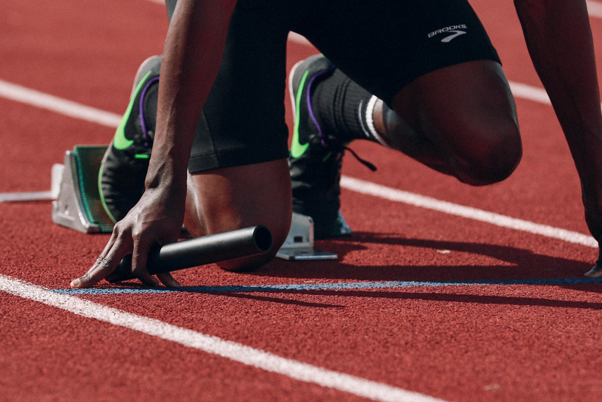 Athlete positioned at the starting blocks on a running track, illustrating lower-leg alignment and foot-to-calf movement patterns often observed in sprinting and jumping activities.