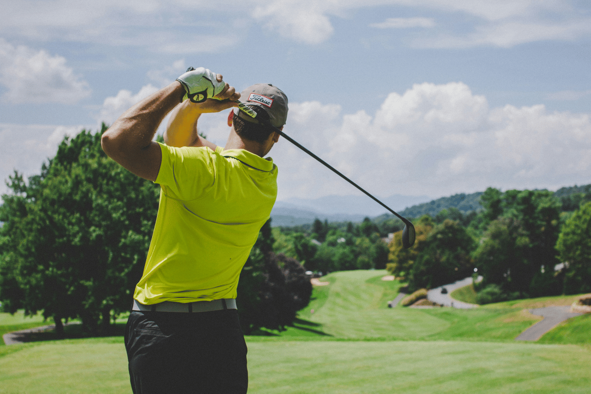 Golfer at full follow-through on a golf course demonstrating the thoracic rotation range of motion affected by T-spine and rib cage soft tissue restriction