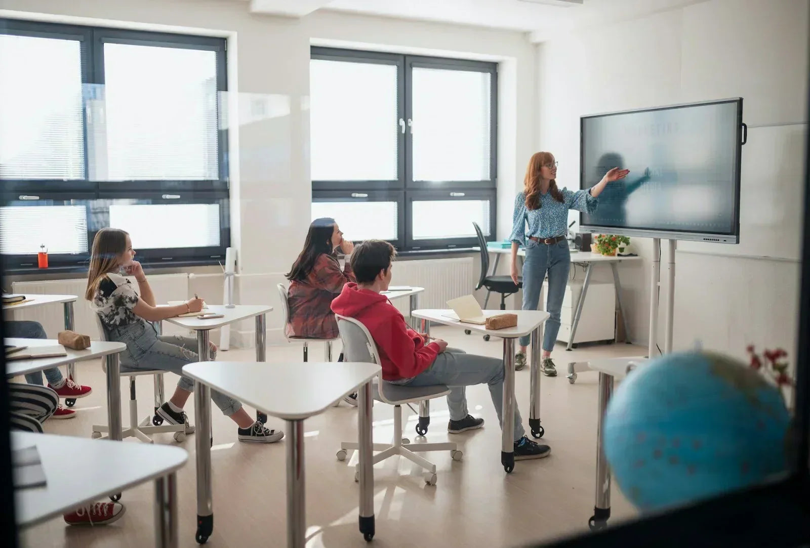 Teacher standing at a digital whiteboard while students sit at desks, representing everyday standing and walking activities that can aggravate or be affected by Tarsal Tunnel Syndrome.