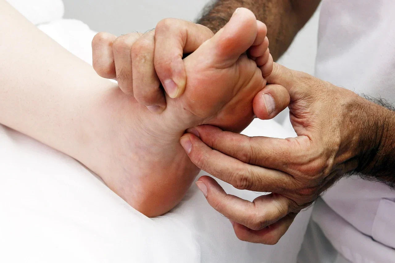 Close-up of a professional performing therapeutic foot massage to relieve tension and support flat feet recovery, promoting arch support, mobility, and daily comfort through at-home techniques.