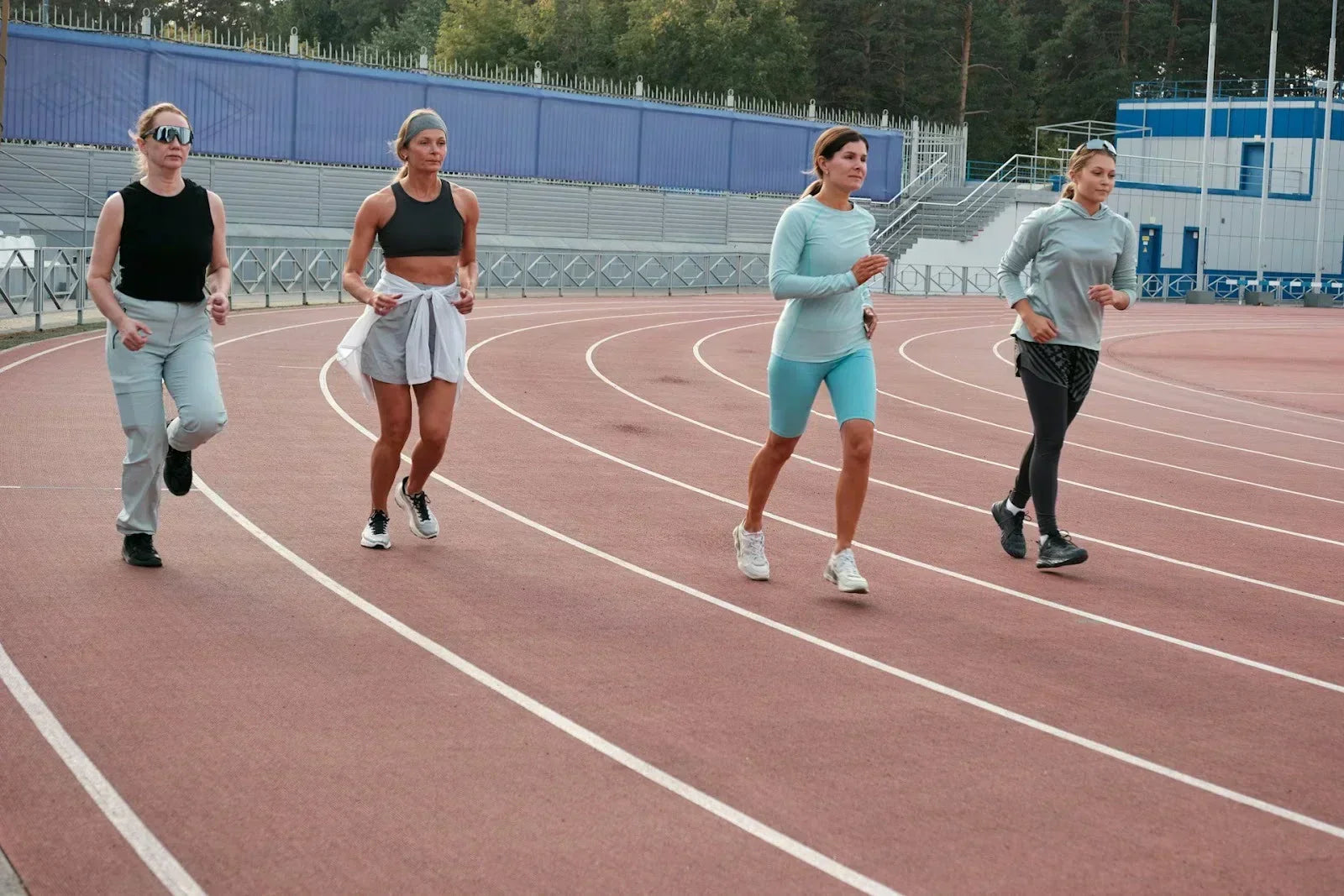 Group of women jogging and walking on an outdoor track, representing movement, endurance, and daily foot and leg health awareness.