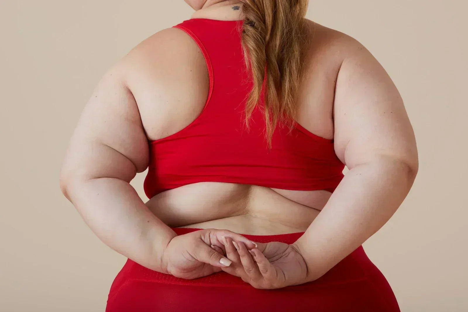 Person in activewear holding their hands behind their back, highlighting body composition and weight-bearing demands relevant to obesity-related foot strain and lower-extremity load.
