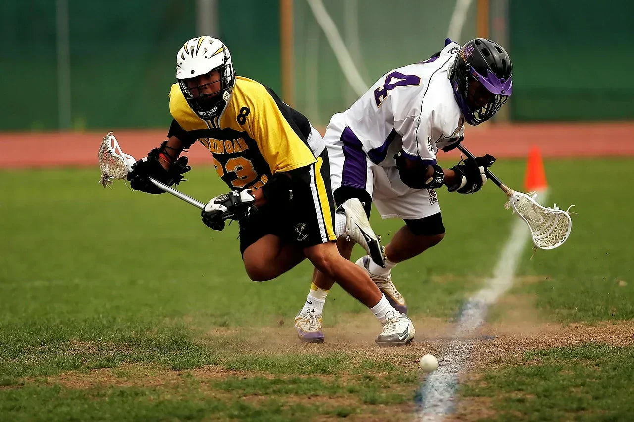 Two lacrosse players competing for a ground ball on the field, highlighting rapid footwork, forefoot loading, and arch mechanics relevant to high-arch performance and recovery.