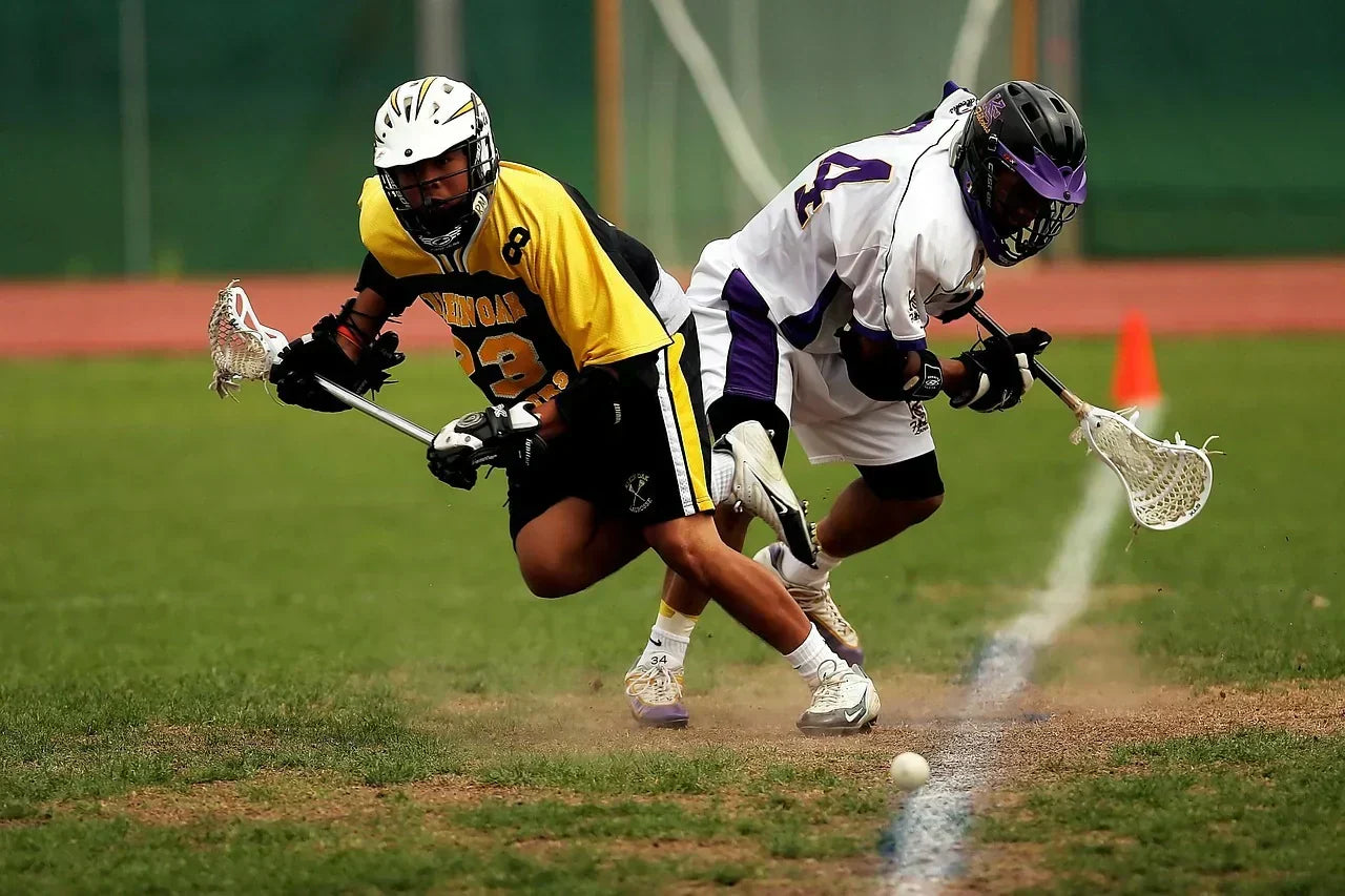 Two lacrosse players competing for a ground ball on the field, highlighting rapid footwork, forefoot loading, and arch mechanics relevant to high-arch performance and recovery.