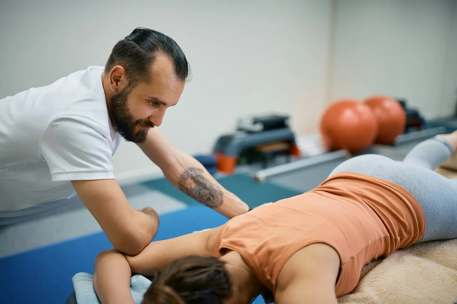 A clinician applying manual therapy to a client’s shoulder, illustrating evidence-based recovery methods such as massage, soft tissue mobilization, and mechanical compression compared in the RƎ LOAD Method™ review of top recovery modalities.