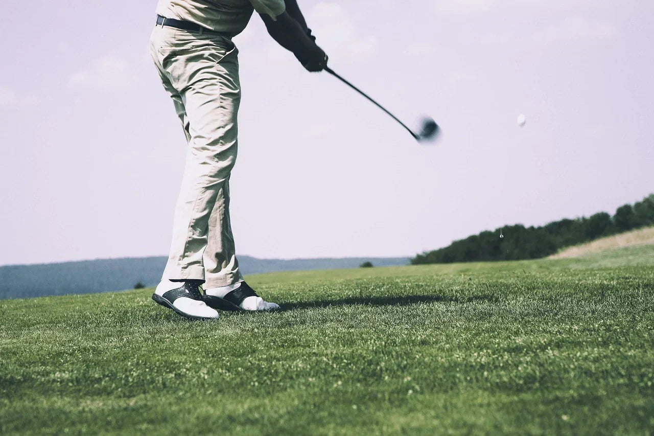 Golfer swinging a club on the fairway, emphasizing foot positioning and forefoot mechanics important for power, balance, and athletic performance.