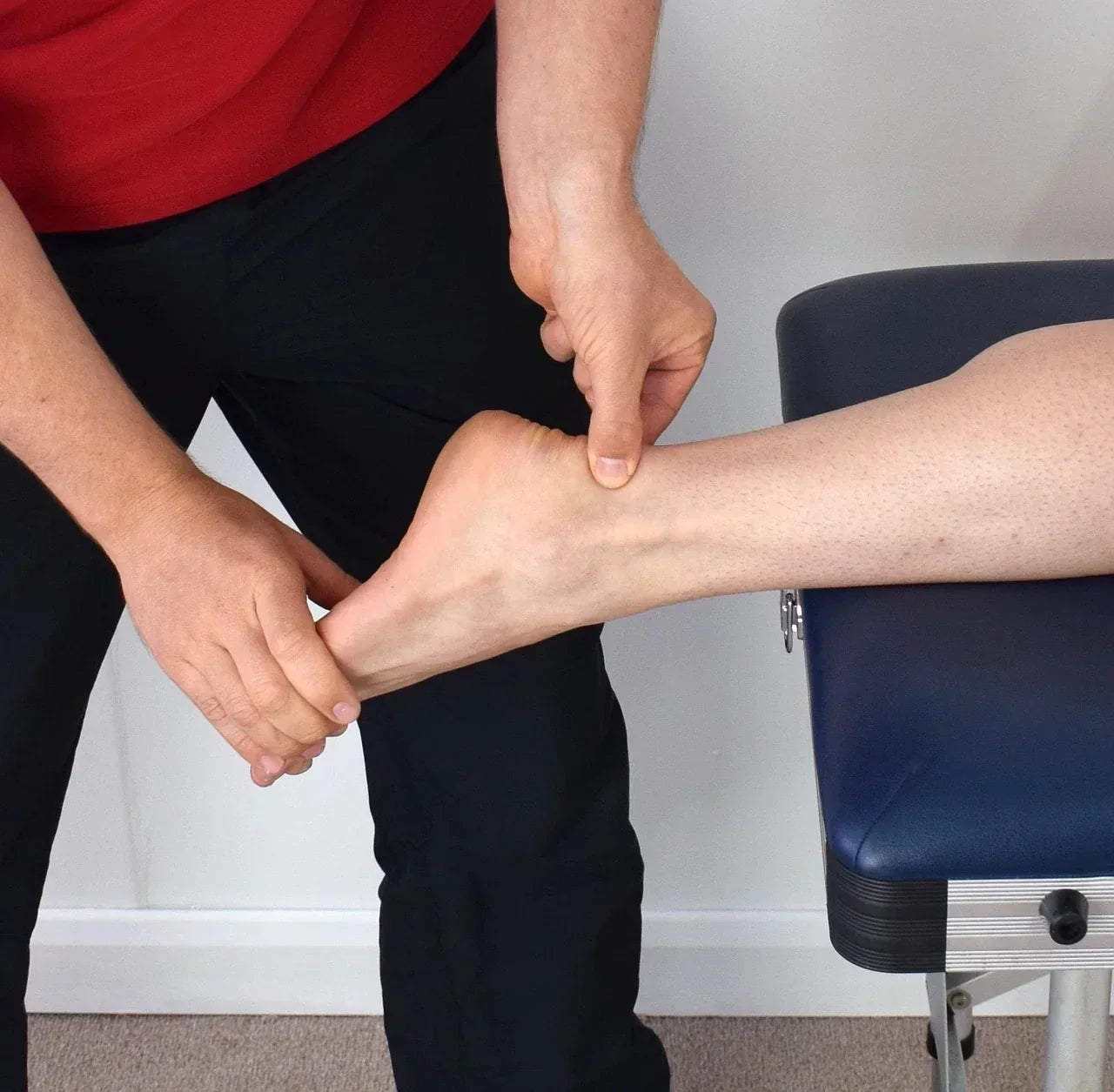 Person exploring lower-leg mobility with gentle manual pressure and movement, demonstrating neutral soft-tissue work for general comfort.